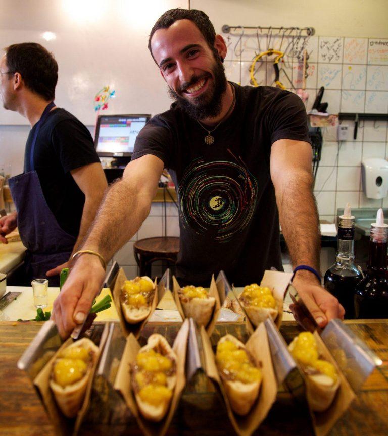 Man at a counter serving Israeli food