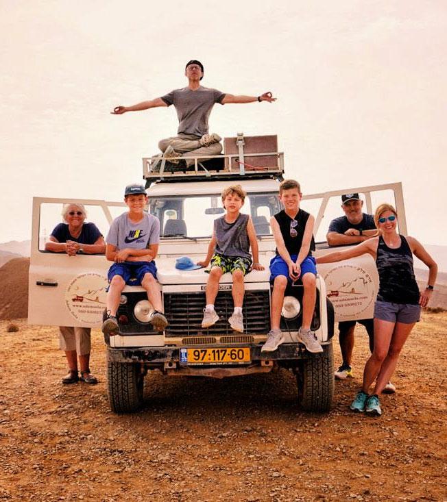 A family sitting on a jeep in the desert in Israel.