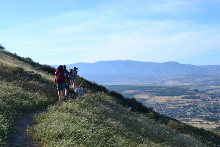 Several hikers on the Jesus Trail with a view of Mt. Arbel in the countryside of Galilee.
