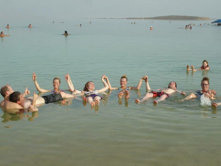 A group of travelers holding hands and floating in the Dead Sea in Israel, with one handicapped traveler being held securely by another.